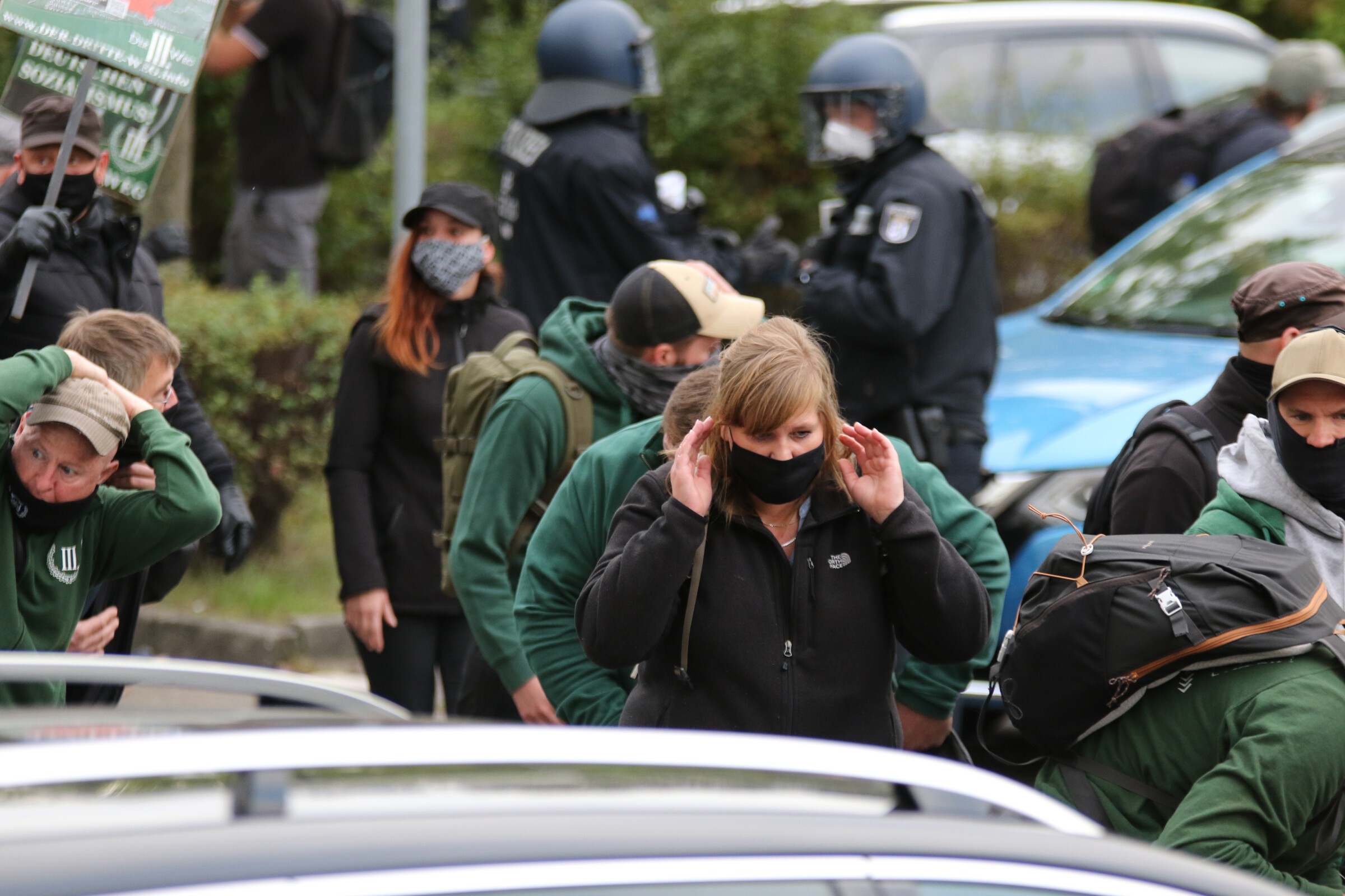 Personen halten sich auf einer Demonstration schützend die Hände über den Kopf