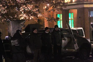 Vier Personen stehen in Parteikleidung der Partei "Der III. Weg" vor einem Auto.