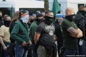 Mehrere vermummte Personen auf einer rechten Demonstration.