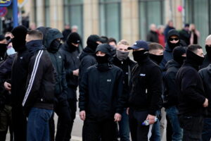 Mehrere vermummte Personen auf einer rechten Demonstration.