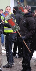 Person, die in der Hand ein Schild der Partei "der dritte Weg" hält.