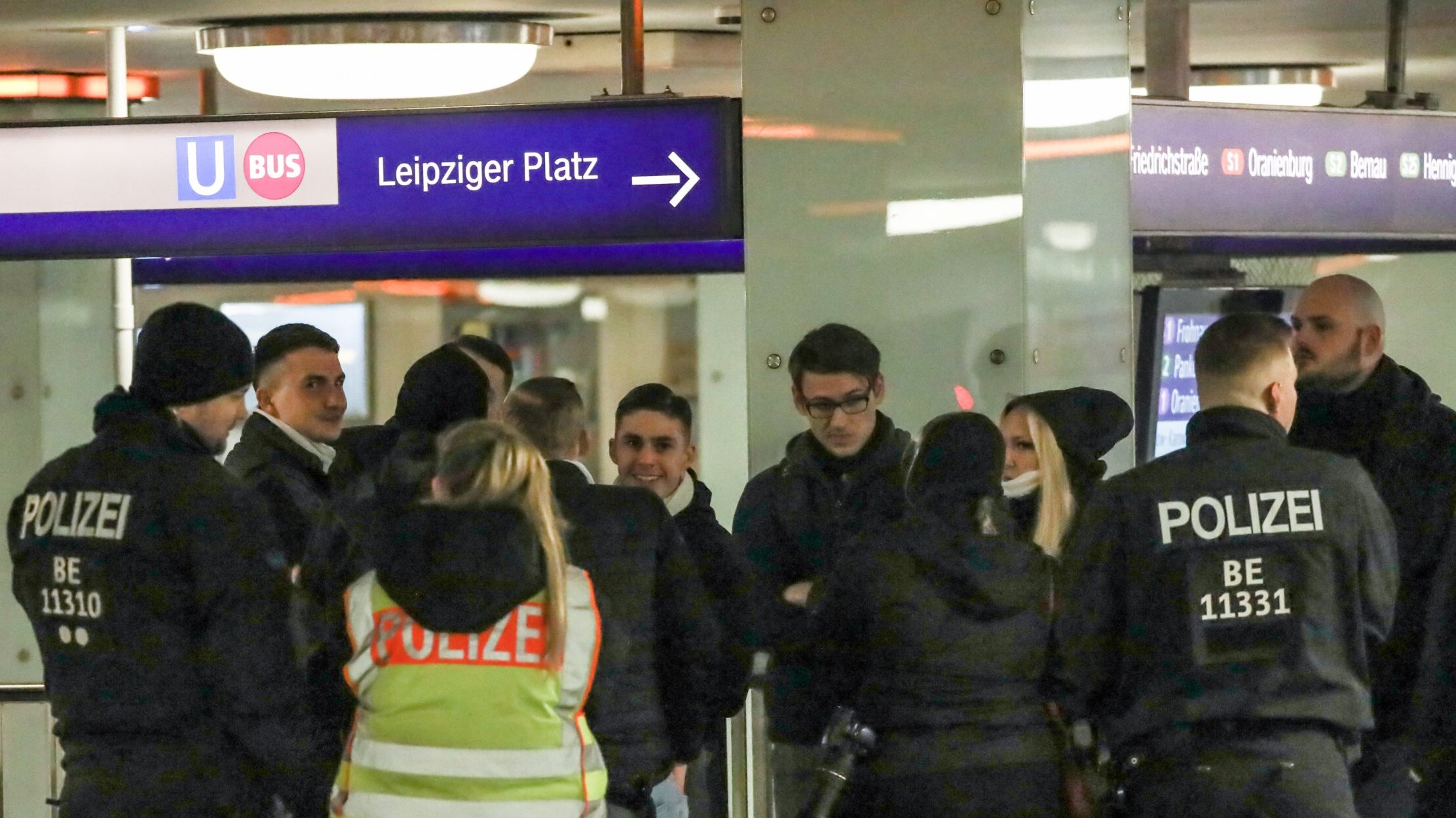 Mehrere Personen in einer Polizeikontrolle in einem Bahnhof.