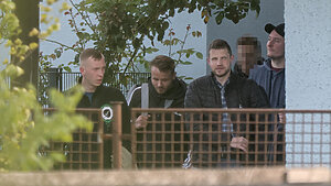 Vier Personen in rechter Szenekleidung und mit Sportsachen kommen aus einer Turnhalle