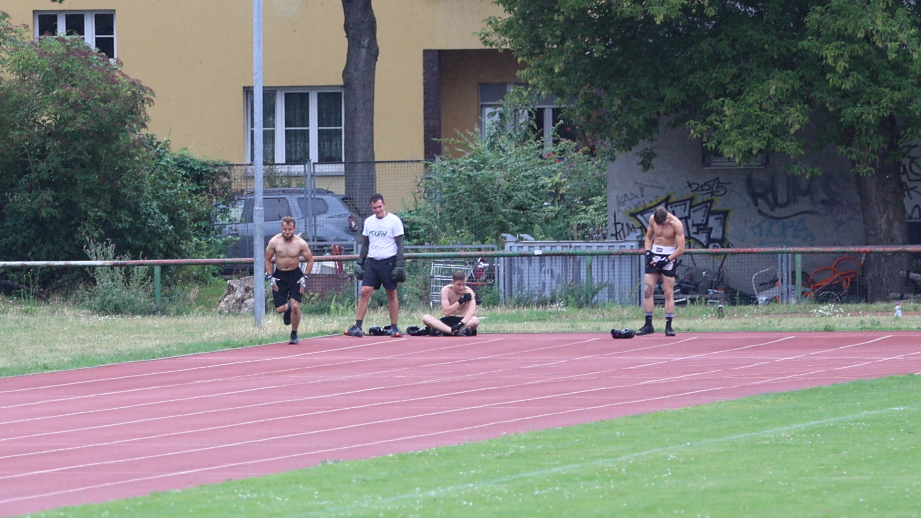 Vier junge Männer mit Kampfsportausrüstung auf einem Sportplatz
